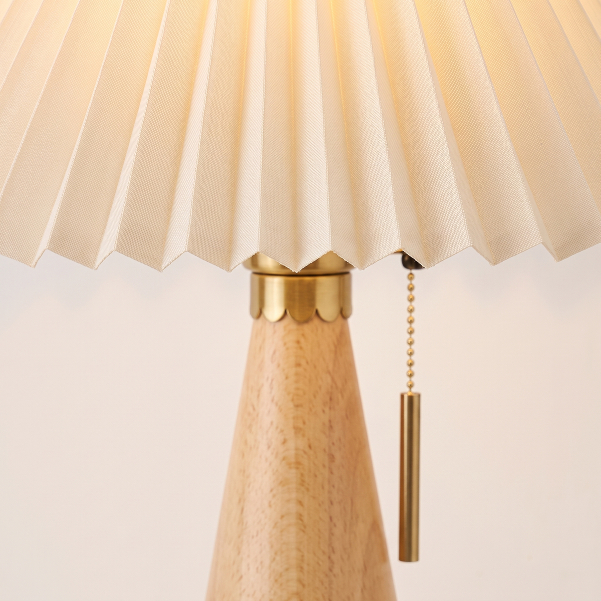 Close up of the brass socket collar and brass pull chain where the pleated shade meets the wood cone