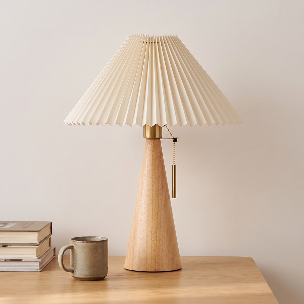 Natural wood pleated table lamp beside a stack of books and a stoneware mug showing its 48cm height