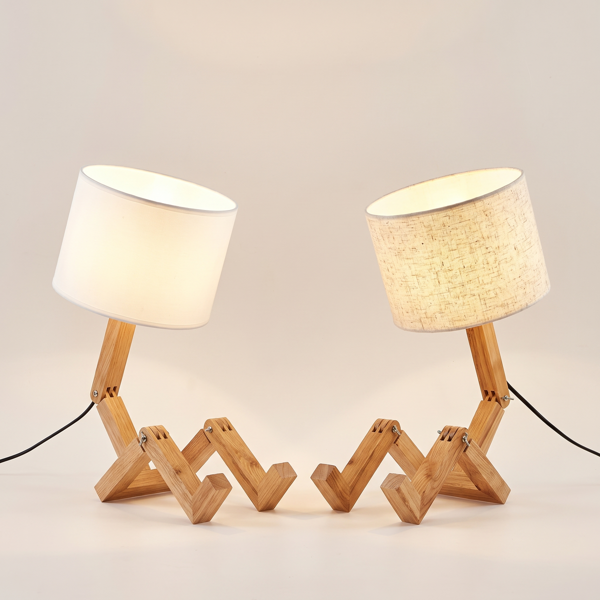 Two jointed wooden robot desk lamps side by side, one with a white shade and one with a beige shade