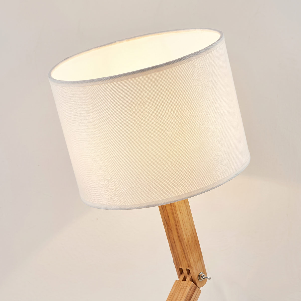 Close up of the white fabric drum shade and the wooden neck bar that carries it