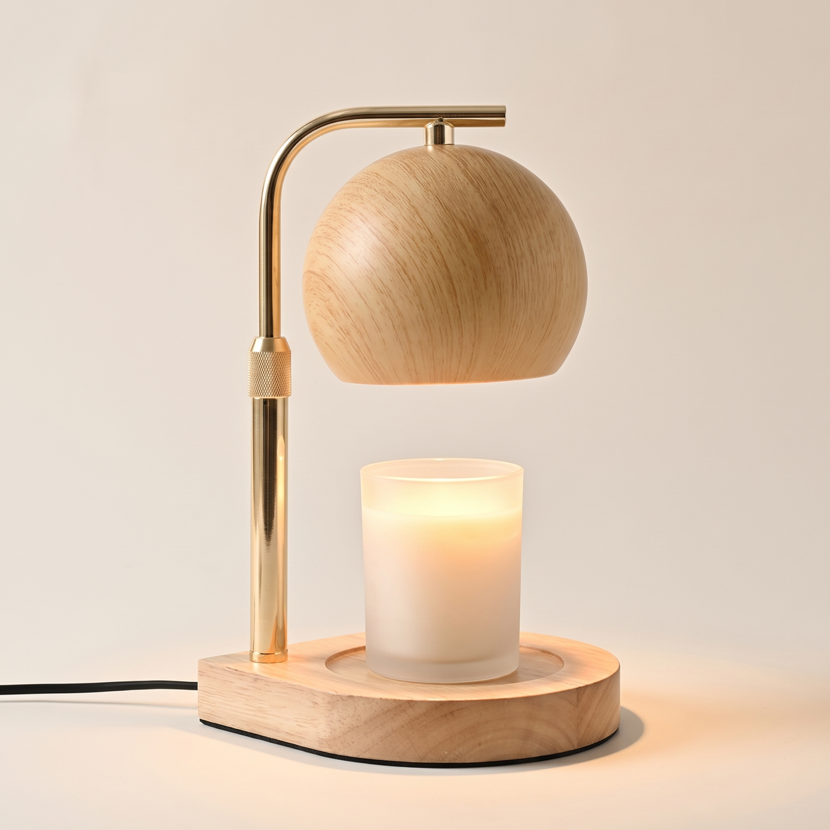 Natural wood candle warmer lamp with a brass arm warming a jar candle from above