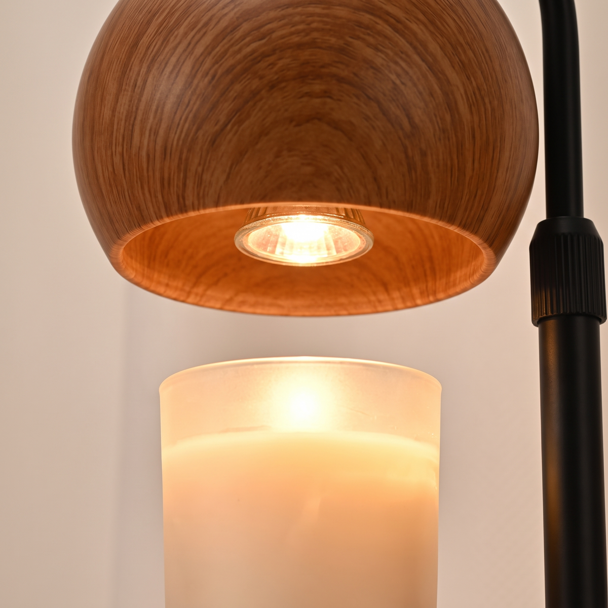 Close up of the wooden dome and the warm bulb above a fully melted candle wax pool