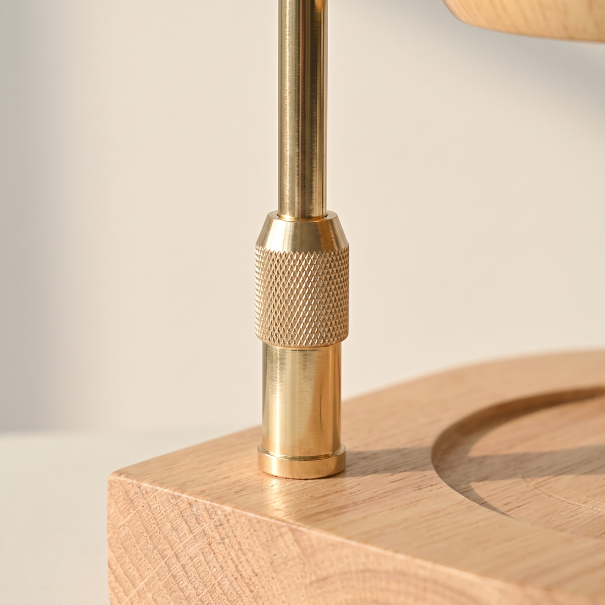 Close up of the knurled brass collar on the arm and the natural wood base