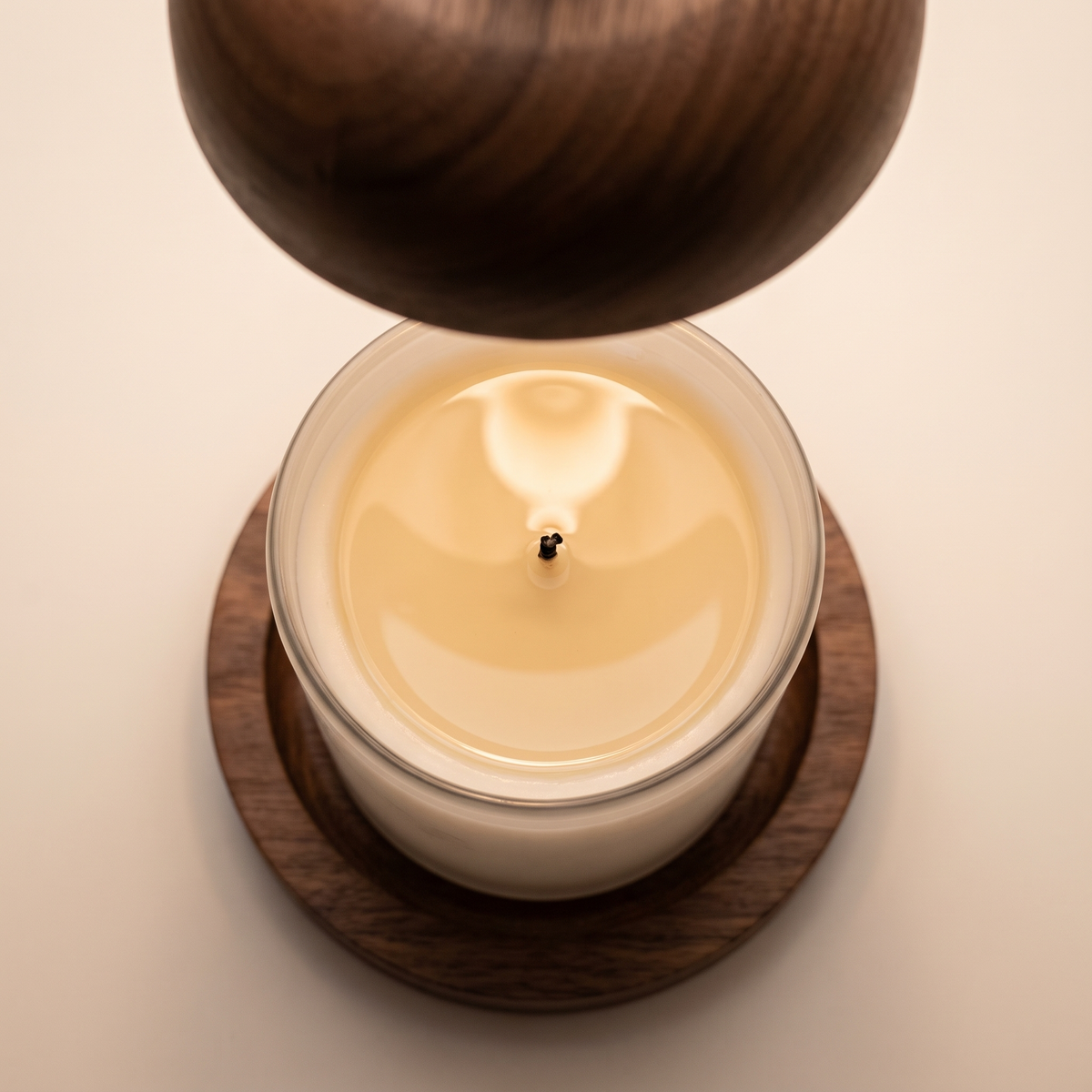 Candle wax melted into a full liquid pool seen from above under the wooden dome