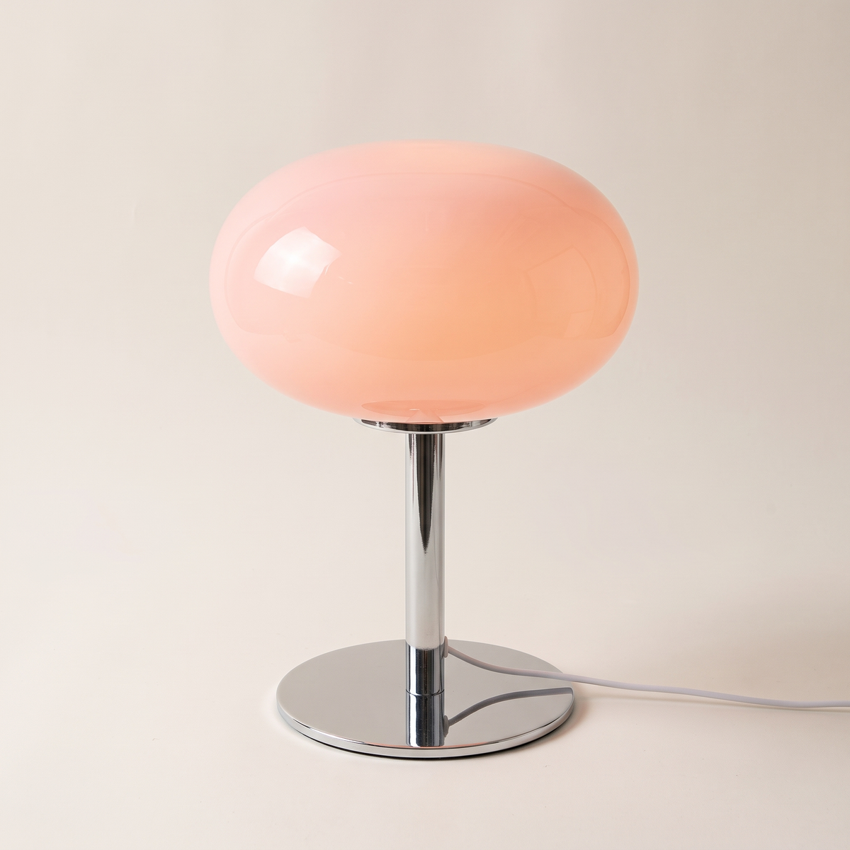 Pink snowball glass table lamp with a single rounded dome shade on a chrome stem