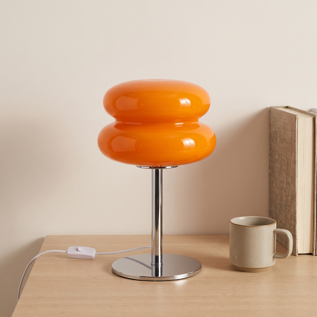 Orange macaron glass table lamp beside a book and a mug showing its 30cm height